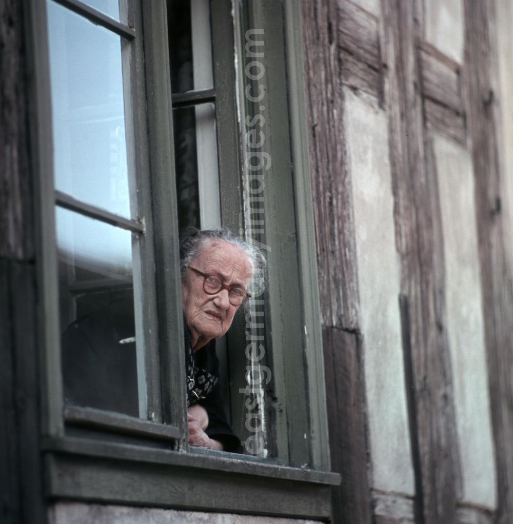 GDR picture archive: Berlin - Eine alte Frau schaut aus dem Fenster ihrer Altbauwohnung in Berlin.