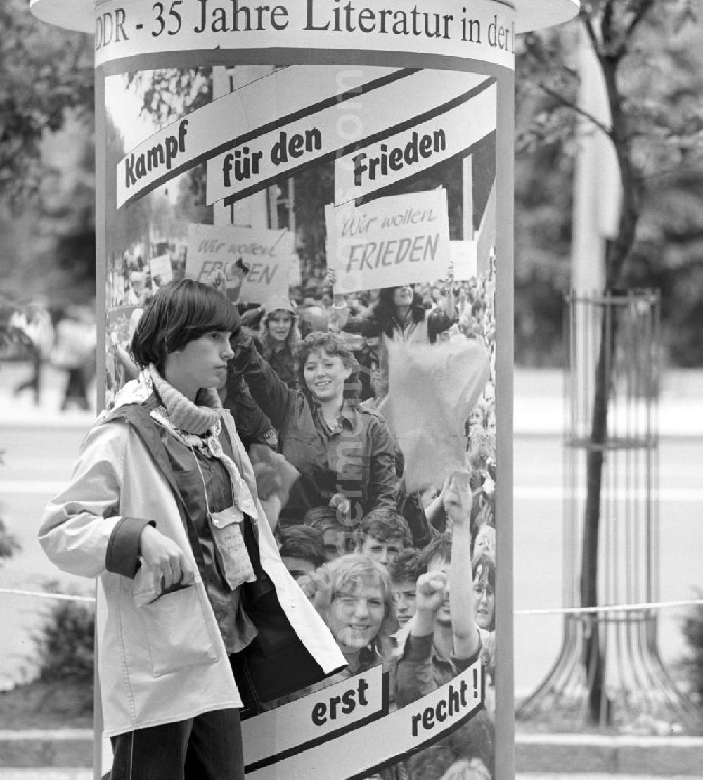 GDR photo archive: Berlin - Zum Pfingsttreffen der FDJ in Berlin steht ein Mädchen an einer Litfaßsäule mit sozialistischer Propaganda. Kampf für den Frieden heißt es auf den Plakaten.