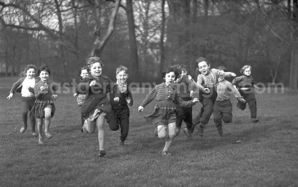 GDR picture archive: Leipzig - Eine Gruppe Vorschulkinder rennt lachend über eine Wiese im Clara-Zetkin-Park in Leipzig.