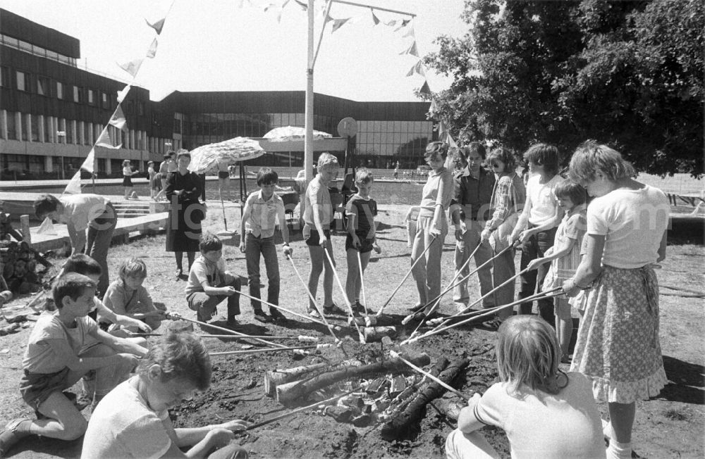 GDR picture archive: Berlin - Children baking bread on an open fire on Children's Day on the grounds of the Pioneer Palace (today: Leisure and Recreation Centre FEZ ) in Berlin Koepenick in the territory of the former GDR, German Democratic Republic
