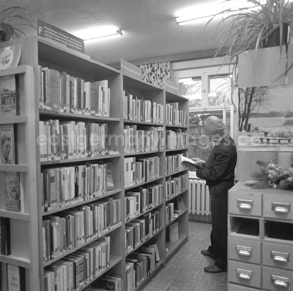 GDR picture archive: Berlin - Veranstaltung mit dem Komponisten Kurt Schwaen in einer Bibliothek in Berlin-Mahlsdorf - Kurt Schwaen steht in einer Regalreihe und blättert in einem Buch.