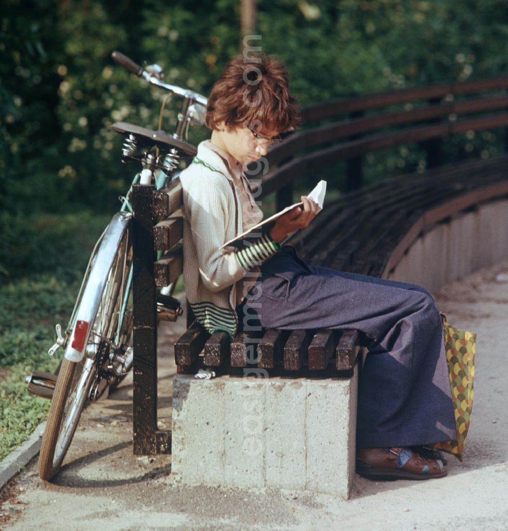 GDR photo archive: Berlin - Ein Junge liest auf einer Bank in einem Park in Berlin ein Buch.