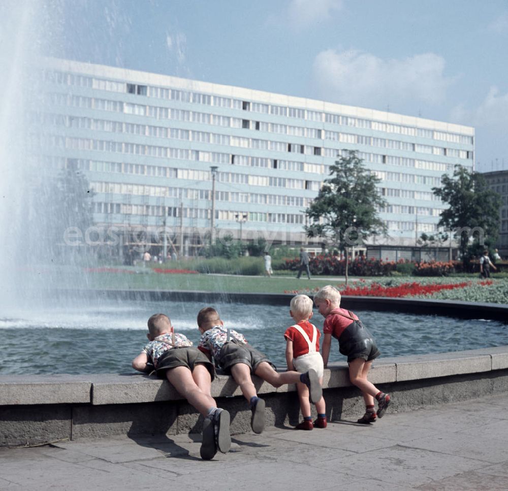 GDR photo archive: Magdeburg - Kinder spielen an einem Springbrunnen am Ulrichplatz im Zentrum von Magdeburg. Die Magdeburger Innenstadt war während des Zweiten Weltkrieges zum großen Teil zerstört worden. Die meisten beschädigten Gebäude wurden in der DDR abgerissen und durch Plattenbauten ersetzt, hier das Bürogebäude der s.g. Blaue Bock im Hintergrund.