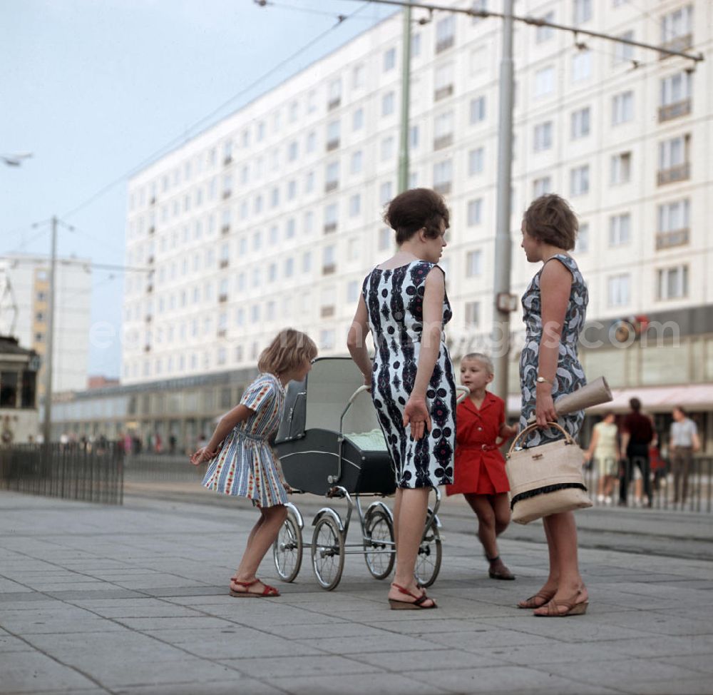 GDR picture archive: Magdeburg - Zwei Frauen mit ihren Kindern unterhalten sich auf der Karl-Marx-Straße, heute Breiter Weg, in Magedeburg. Die Magdeburger Innenstadt war während des Zweiten Weltkrieges zum großen Teil zerstört worden. Die meisten beschädigten Gebäude wurden in der DDR abgerissen und durch Plattenbauten ersetzt.