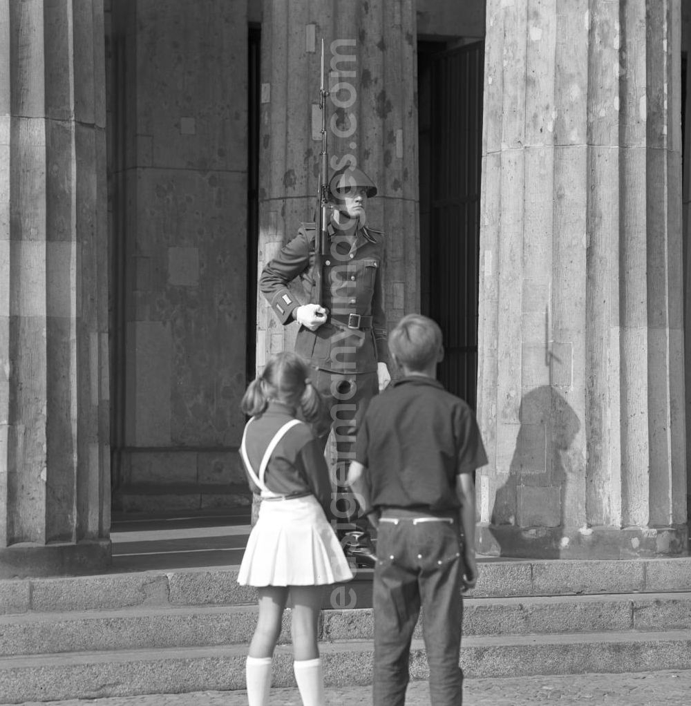 GDR photo archive: Berlin - Zwei Kinder betrachten einen vor der Neuen Wache Unter den Linden in Berlin postierten NVA-Soldaten9. Die ständige Ehrenwache der Nationalen Volksarmee stand an dem historischen Bau, der zu DDR-Zeiten als zentrale Gedenkstätte für die Opfer des Faschismus und Militarismus eingerichtet war.