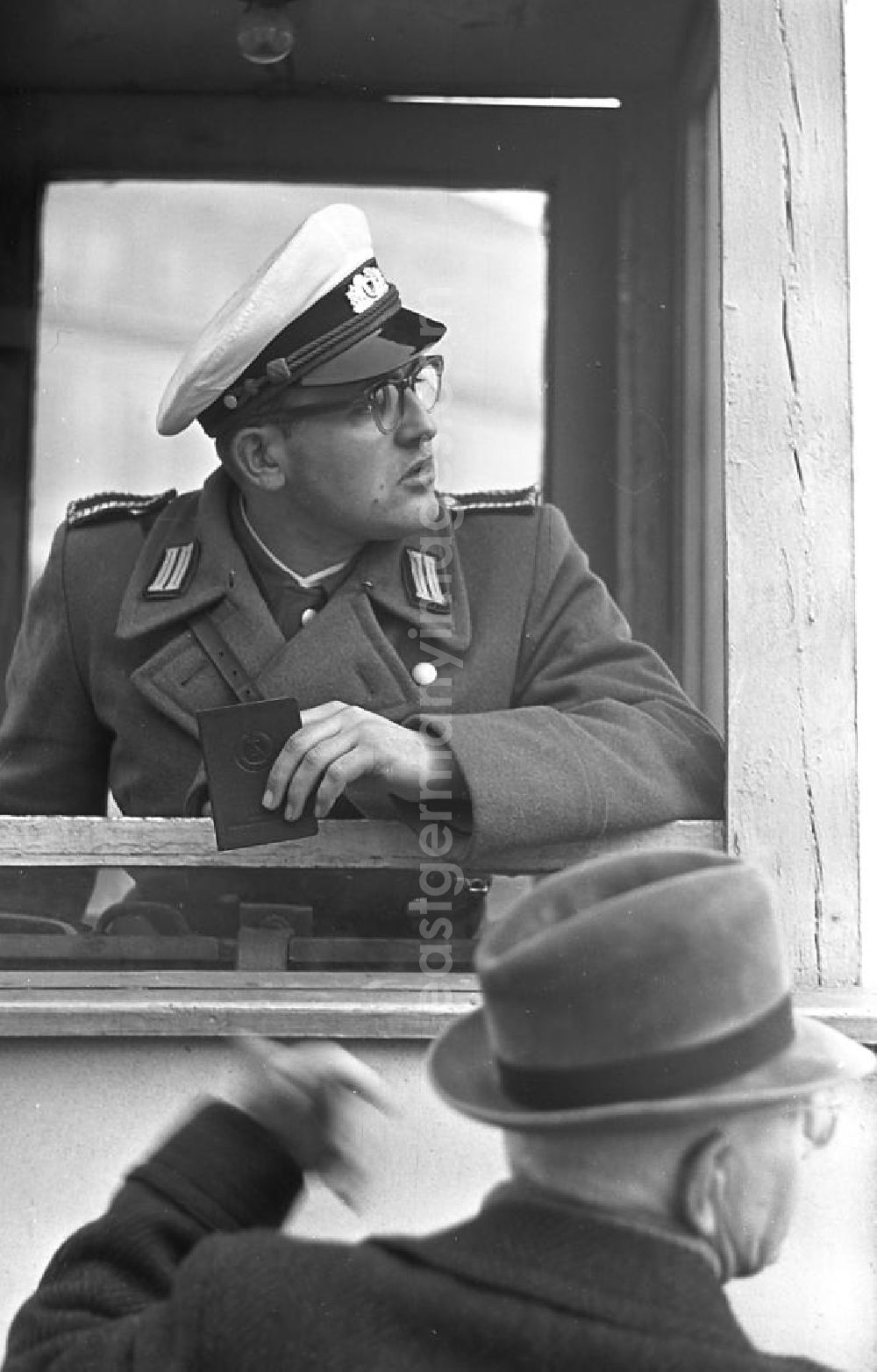GDR photo archive: Leipzig - Ein Polizist kontrolliert einen Passanten aus seinem Wachhäuschen am Karl-Marx-Platz in Leipzig.