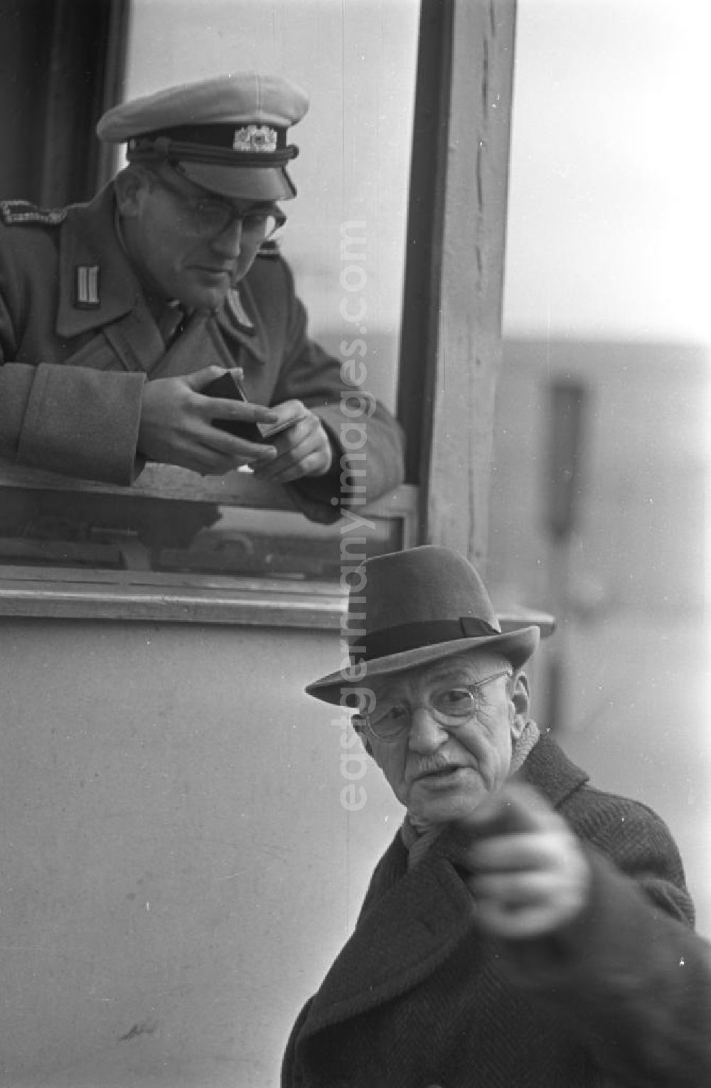 GDR picture archive: Leipzig - Ein Polizist kontrolliert einen Passanten aus seinem Wachhäuschen am Karl-Marx-Platz in Leipzig.