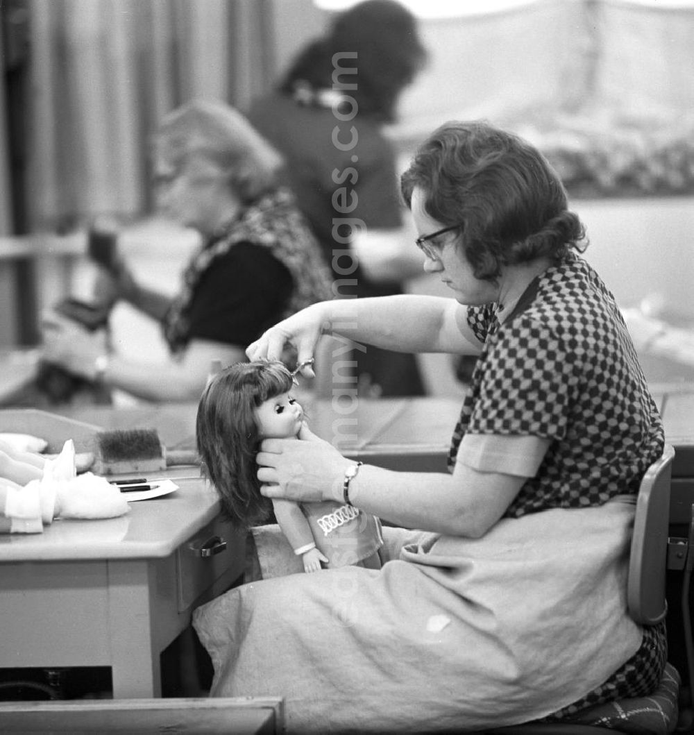GDR picture archive: Sonneburg - Eine Mitarbeiterin des VEB Kombinat Spielwaren Sonneberg sonni frisiert eine fertige Puppe, bevor sie für den Verkauf verpackt wird. Die Sonneberger Puppen waren nicht nur in der DDR beliebt, sondern trugen den Namen der Stadt in alle Welt.