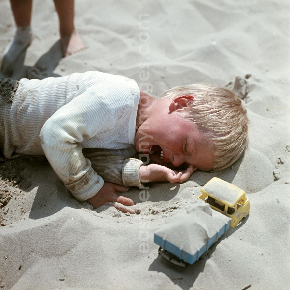 GDR photo archive: Ahlbeck - Ein Junge liegt weinend im Sand am Ostseestrand bei Ahlbeck auf der Insel Usedom.