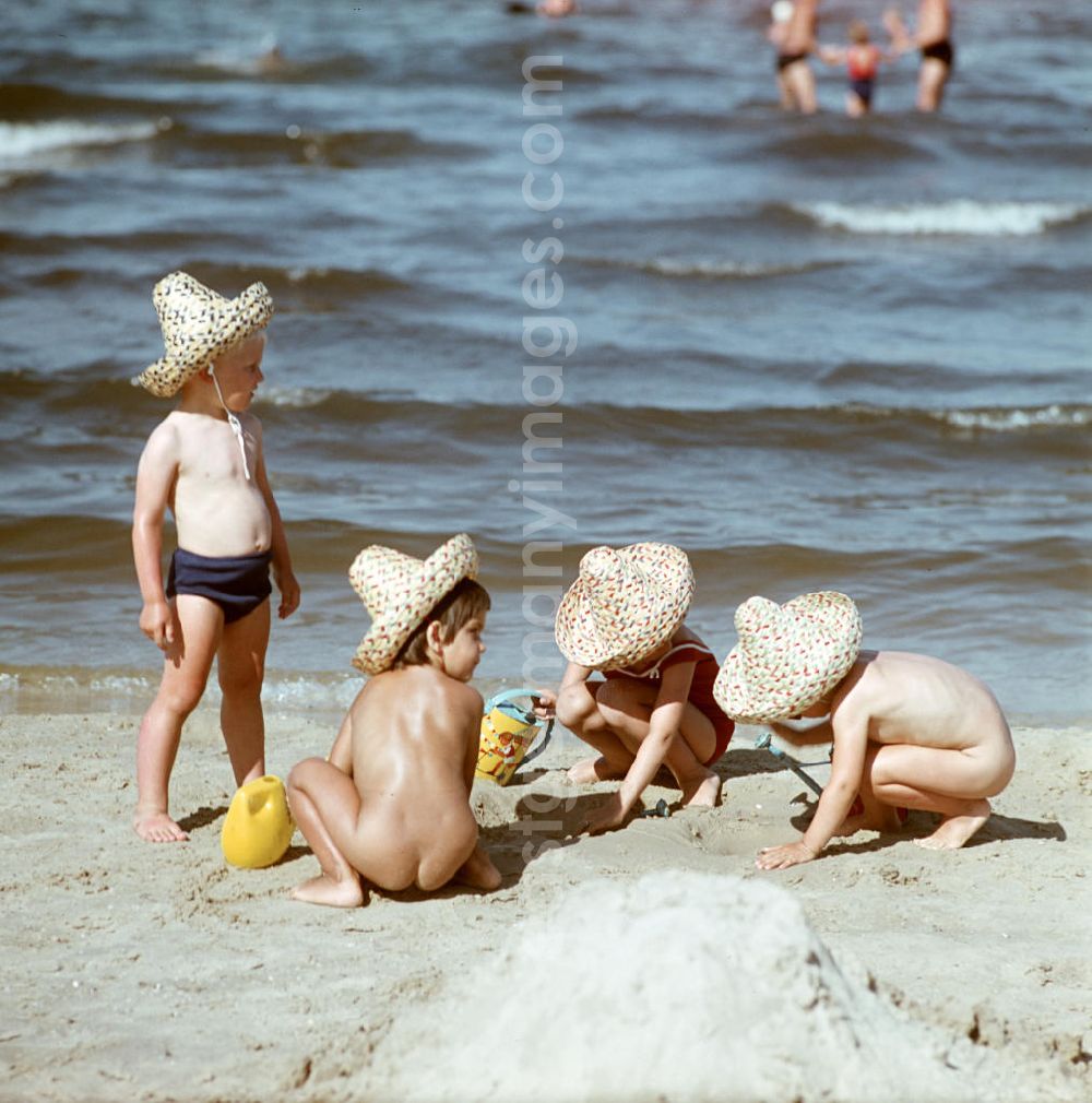 GDR picture archive: Ahlbeck - Kinder mit Strohhüten spielen am Ostseestrand bei Ahlbeck auf der Insel Usedom im Sand.