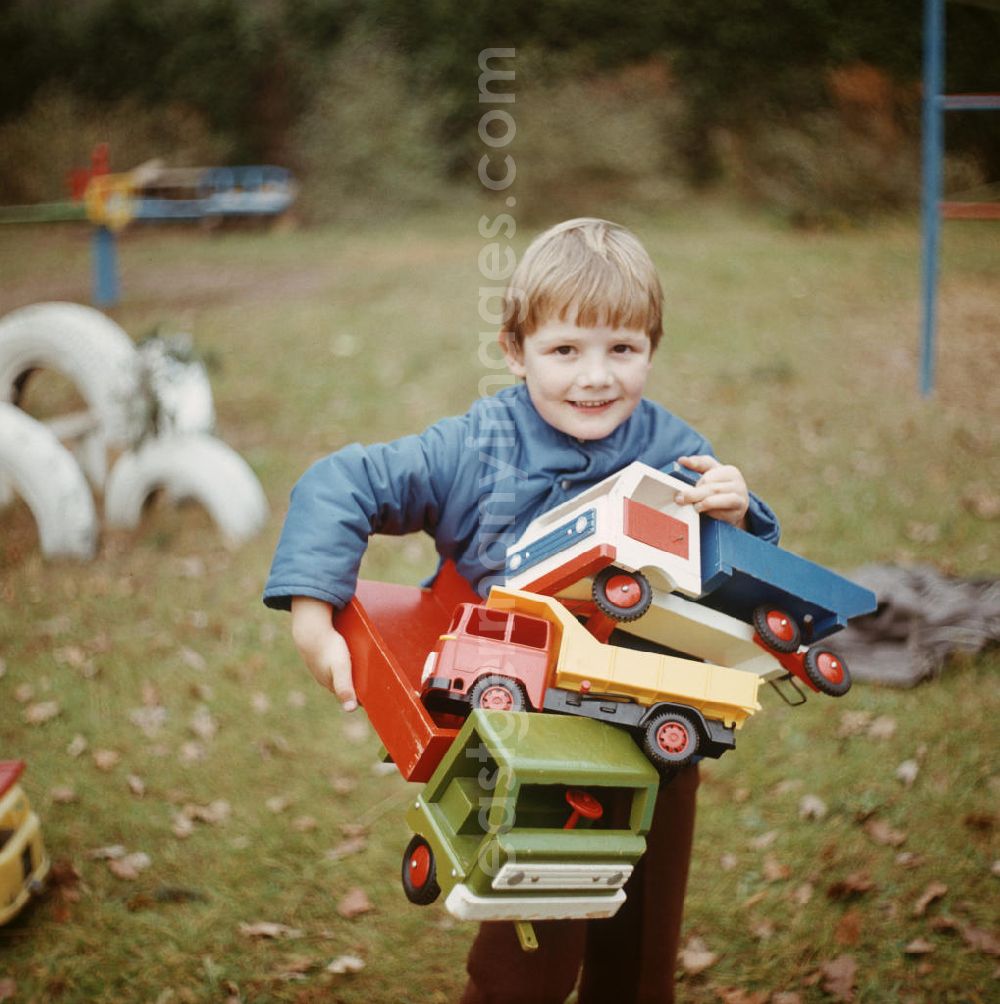 GDR image archive: Bad Saarow - Im Kinderheim Bad Saarow trägt ein Junge Spielzeuglaster auf seinem Arm.
