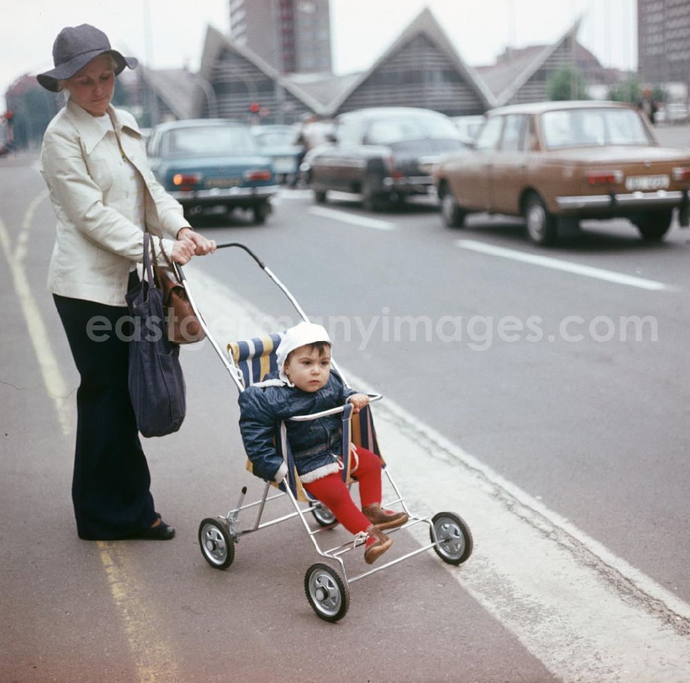 GDR photo archive: Berlin - Eine Frau überquert mit ihrem Kind im Kinderwagen die Gertraudenstraße in Berlin-Mitte. Im Hintergrund die Großgaststätte Ahornblatt, die im Jahr 200