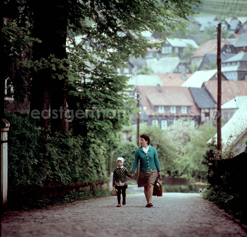 GDR photo archive: Deesbach - Eine Frau geht mit ihrer Tochter auf einer Straße in Deesbach im Thüringer Wald. Der Thüringer Wald mit seinen Wander- und Erholungsmöglichkeiten war ein beliebtes Urlaubsziel in der DDR.