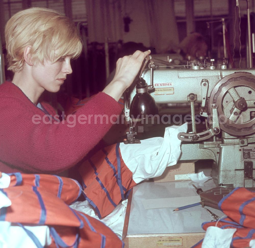 GDR photo archive: Berlin - Eine Mitarbeiterin des VEB Berliner Damenmoden näht an einer Nähmaschine der Marke Textima Damenoberbekleidung.