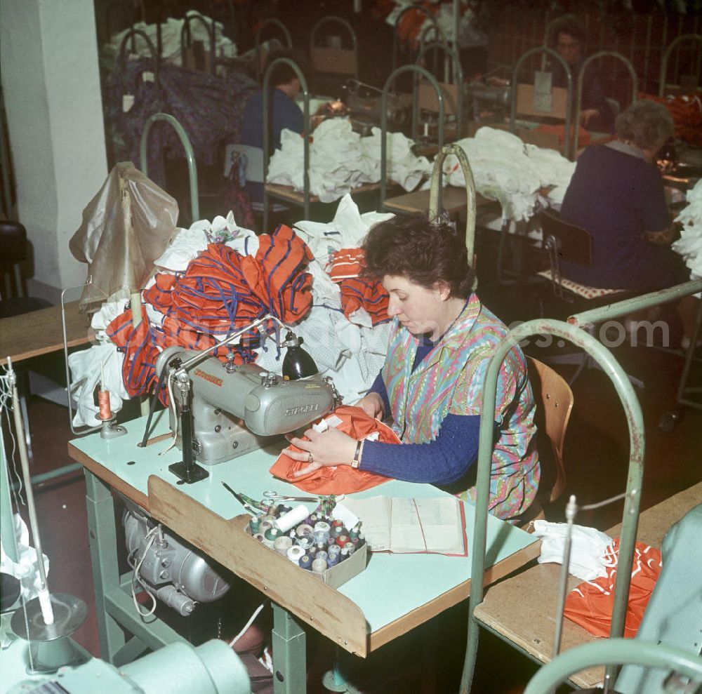 GDR picture archive: Berlin - Eine Mitarbeiterin des VEB Berliner Damenmoden näht an einer Nähmaschine der Marke Strobel Damenoberbekleidung.