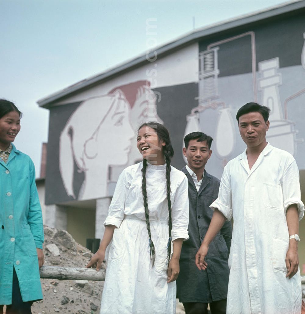 GDR photo archive: Berlin - Vietnamesische Praktikanten stehen vor den Gebäuden des VEB Berlin-Chemie, wo sie ihre Ausbildung absolvieren. Vietnamesen bildeten in der DDR die größte Gruppe an Arbeitskräfte aus den sozialistischen Bruderländern.