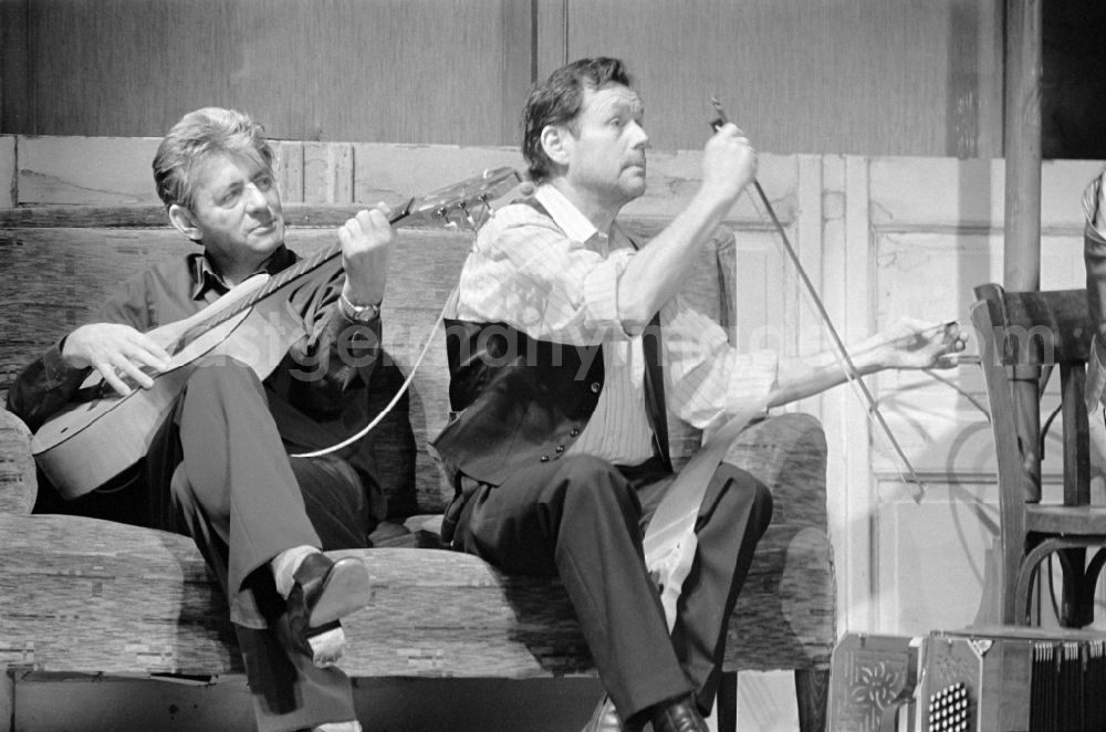 GDR photo archive: Berlin - German Theatre Berlin - Berlin Songs From Then And Yesterday. Actors / actresses and performers in a theatre - scene and stage set in the Mitte district of Berlin, the former capital of the GDR, German Democratic Republic. On the sofa on stage - on the left Rolf Ludwig with guitar and on the right Reimar Johannes Baur plays on a so-called singing saw with a violin bow