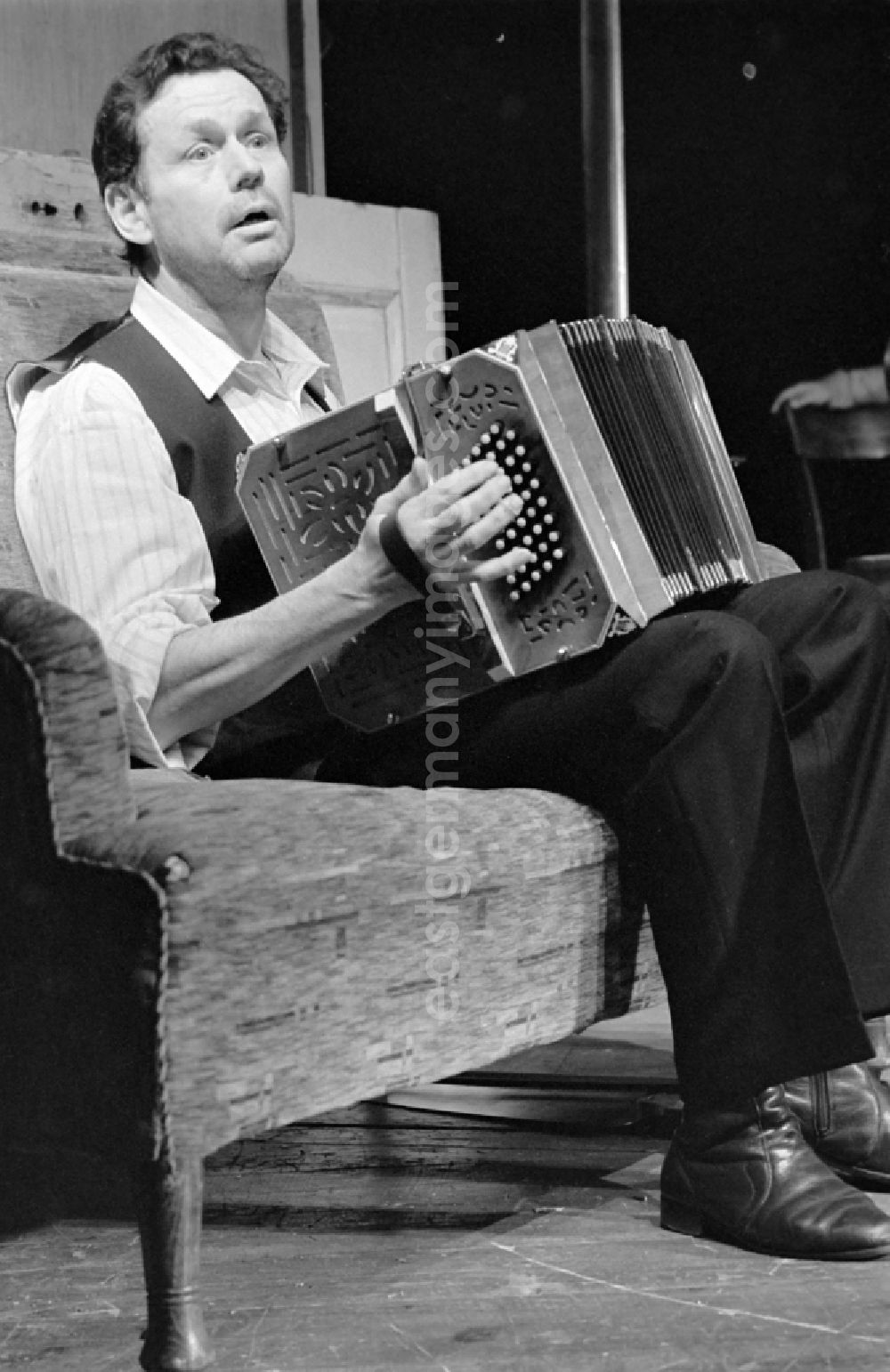 GDR picture archive: Berlin - German Theatre Berlin - Berlin Songs From Then And Yesterday. Actors and performers in a theatre - scene and stage set in the Mitte district of Berlin, the former capital of the GDR, German Democratic Republic. On stage - Reimar Johannes Baur with accordion on the sofa