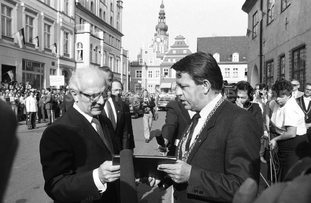 GDR photo archive: Greifswald - Besuch von Erich Honecker anlässlich der Domweihe St. Nikolai. Klaus Ewald, Oberbürgermeister Greifswald, übergibt Erich Honecker, Generalsekretär DDR, Dokumentenmappe. Drumherum Pressevertreter.