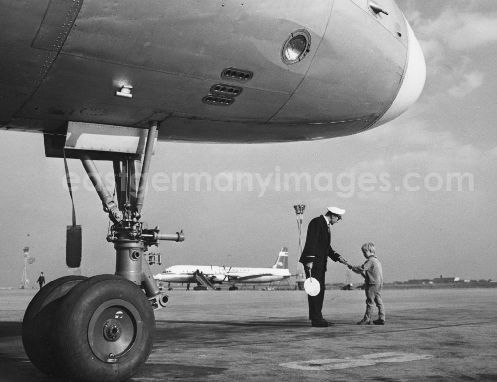 GDR photo archive: Schönefeld - A marshaller the INTERFLUG talking to a boy on the tarmac at the airport at Schoenefeld in what is now the state of Brandenburg. In the foreground the suspension of IL-18. In the background is a propeller aircraft the airline INTERFLUG with gangway