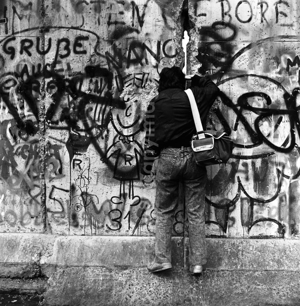 GDR photo archive: Berlin - Mitte - A photographer photographed through a crack in the Berlin Wall in Berlin