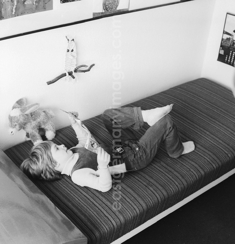 GDR image archive: Berlin - A child lies on a bed in my kids and reading in Berlin, the former capital of the GDR, the German Democratic Republic