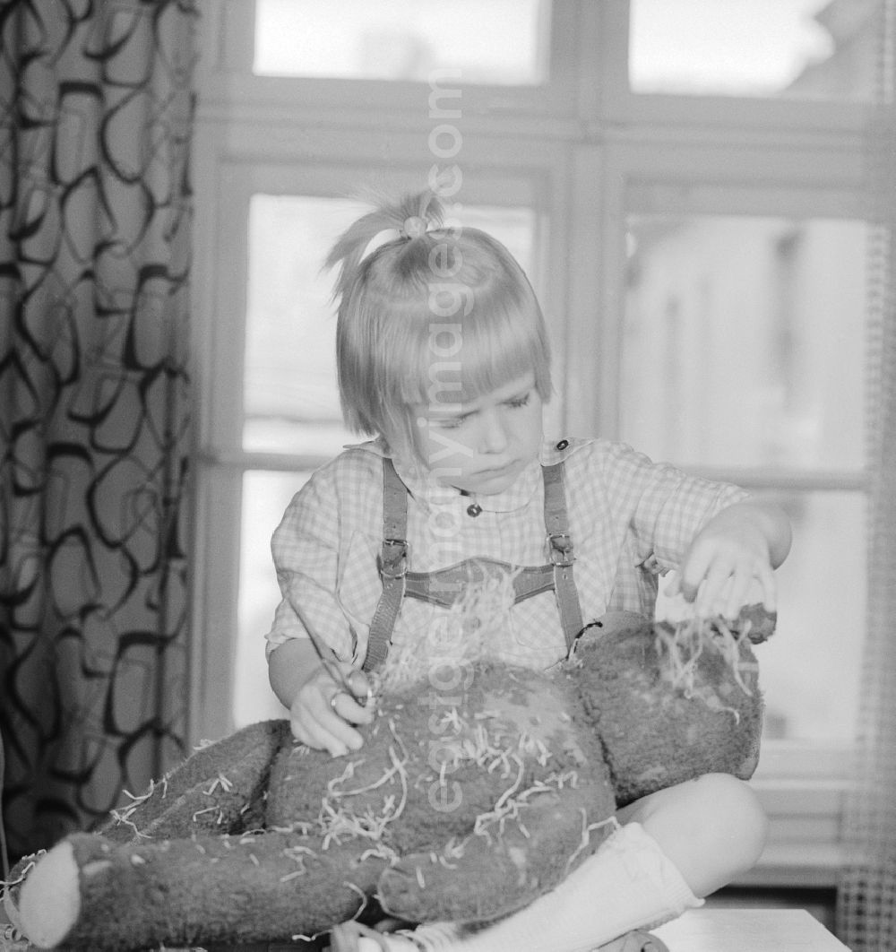 GDR photo archive: Berlin - A child cuts up a teddy bear in Berlin, the former capital of the GDR, German Democratic Republic
