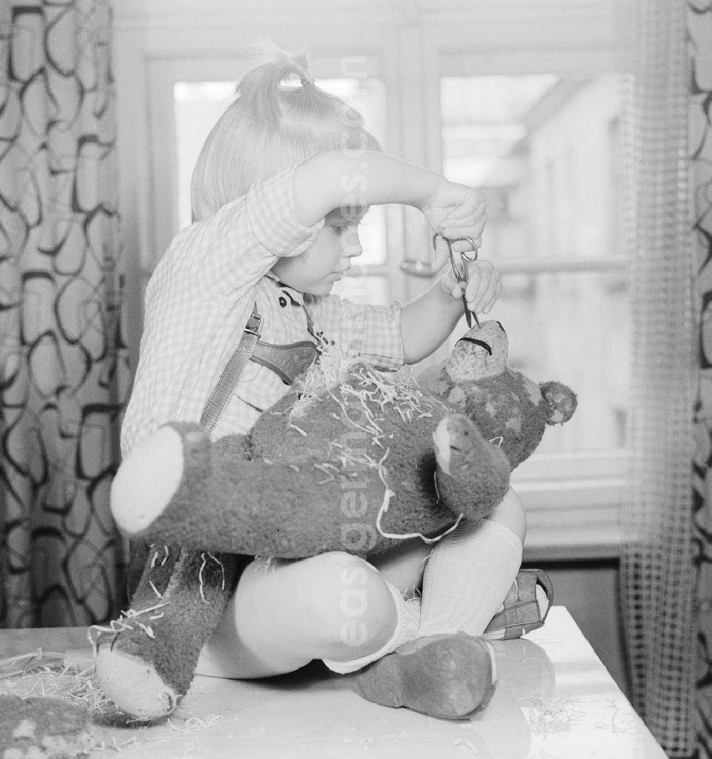 GDR picture archive: Berlin - A child cuts up a teddy bear in Berlin, the former capital of the GDR, German Democratic Republic