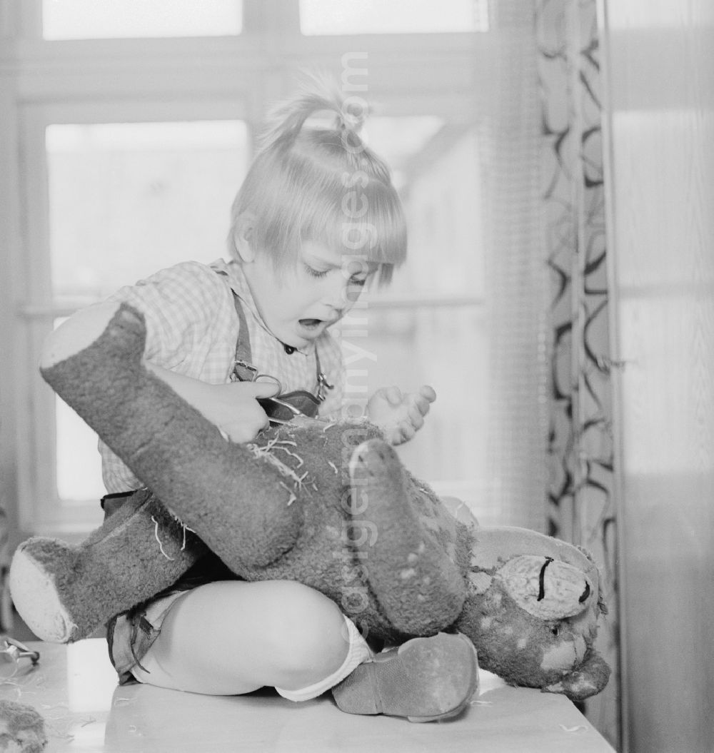 GDR photo archive: Berlin - A child cuts up a teddy bear in Berlin, the former capital of the GDR, German Democratic Republic