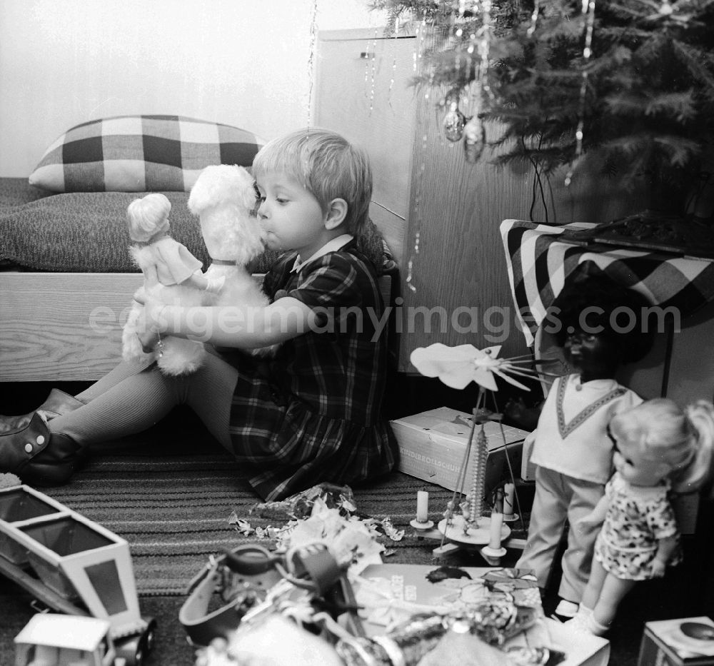 GDR photo archive: Berlin - A small child plays with his Christmas presents under the Christmas tree in Berlin, the former capital of the GDR, German democratic republic
