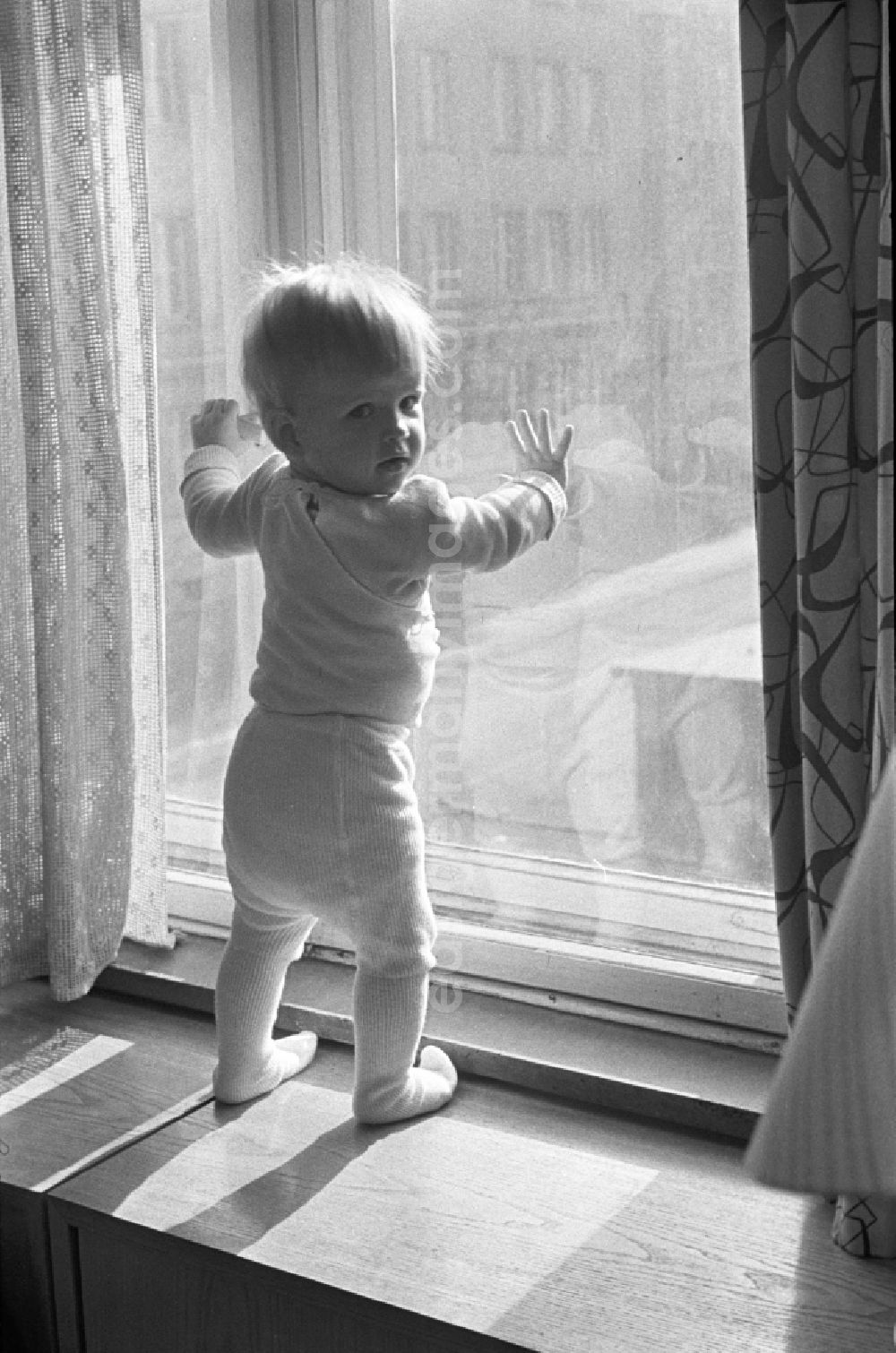GDR image archive: Berlin - Friedrichshain - A small child with tights standing on the window sill at the window in Berlin