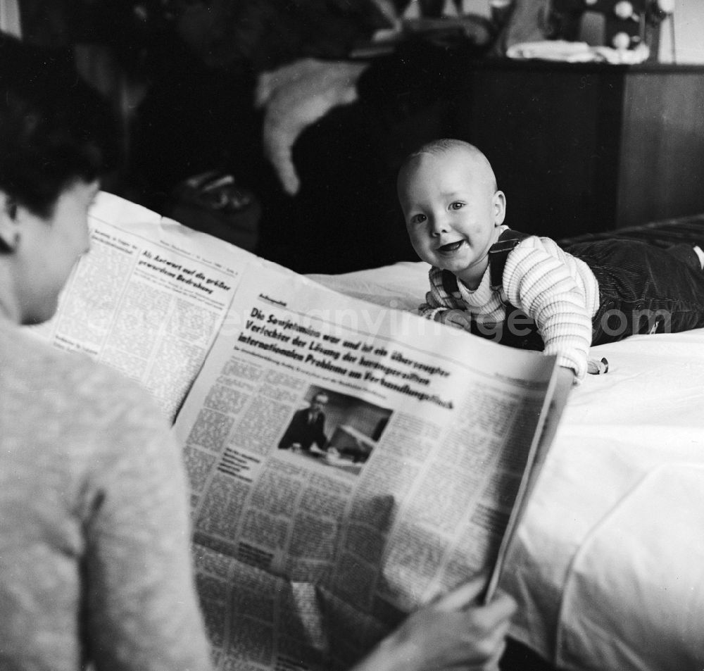 Berlin: A toddler on a playmat in Berlin, the former capital of the GDR, the German Democratic Republic. In the foreground, a daily newspaper