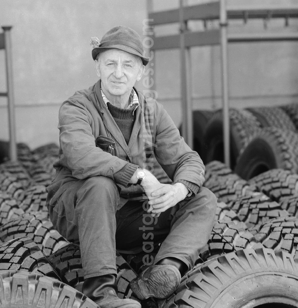 GDR picture archive: Berlin - An elderly man with hat sitting on tires in a spare parts store in Berlin