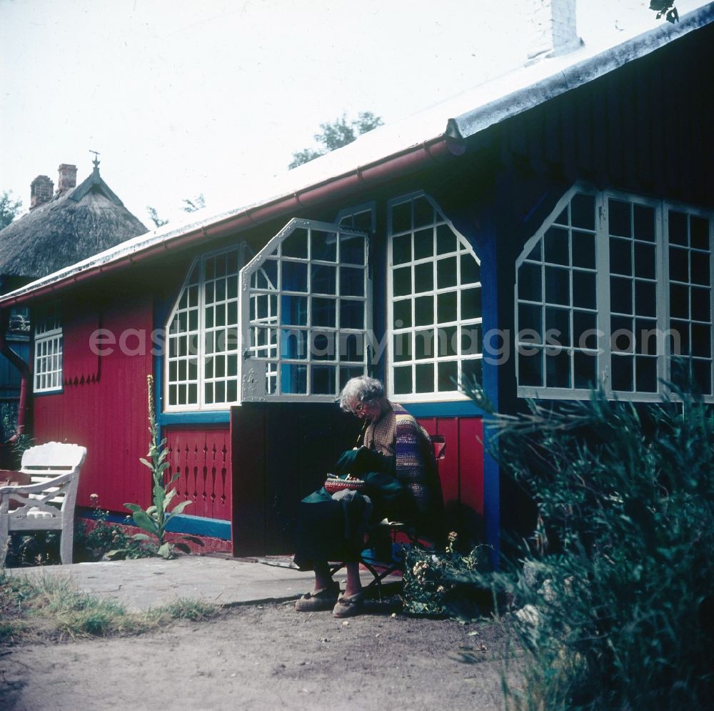 Ahrenshoop: An older man sits before his red summer small house and sews in Ahrenshoop in the federal state Mecklenburg-West Pomerania in the area of the former GDR, German democratic republic