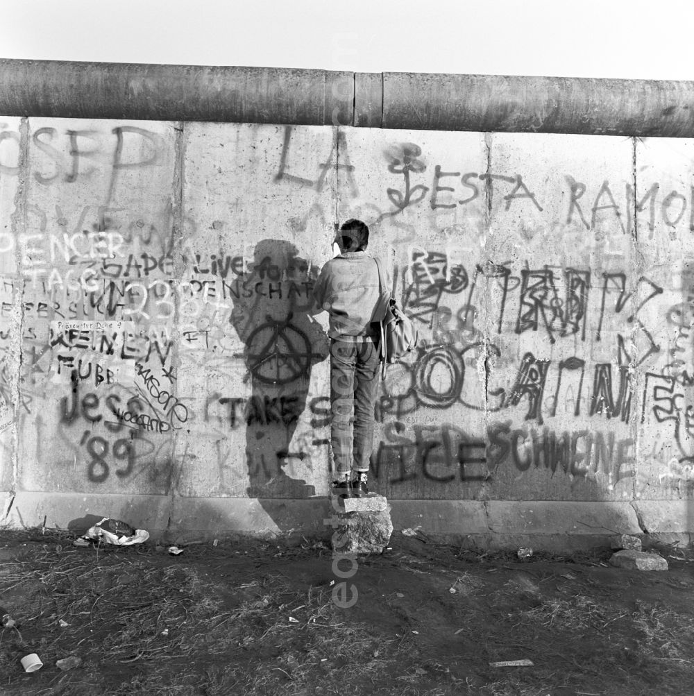 GDR picture archive: Berlin - Mitte - A man photographs through a crack in the Berlin Wall in Berlin