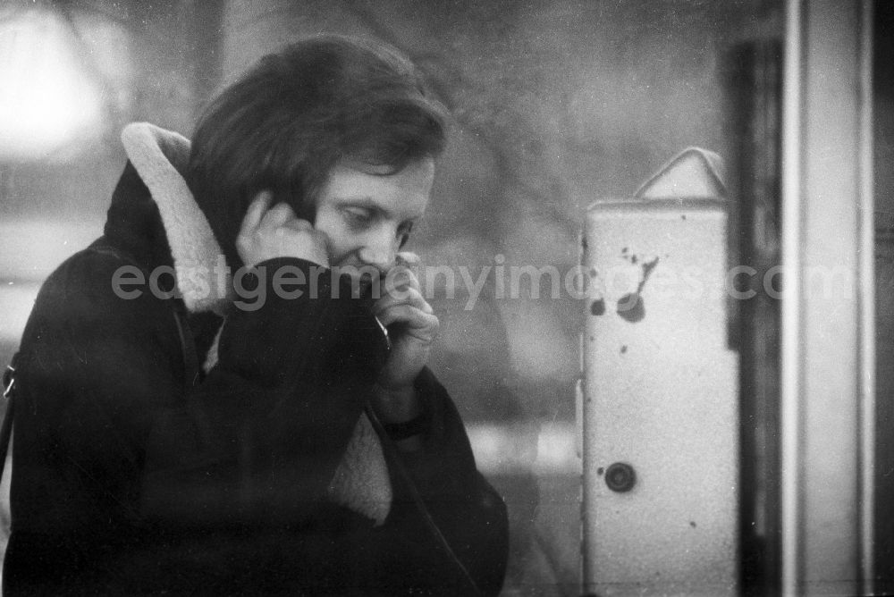 GDR photo archive: Berlin - A man on the phone with a payphone in a public telephone booth in Berlin, the former capital of the GDR, German Democratic Republic