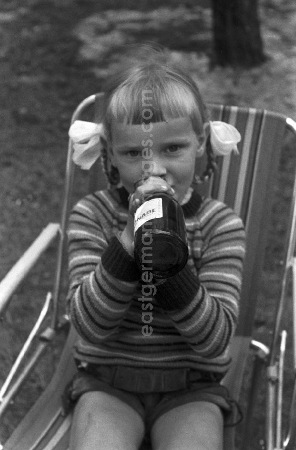 GDR picture archive: Malge - A girl with pigtails drinking from a glass bottle of lemonade in Malge