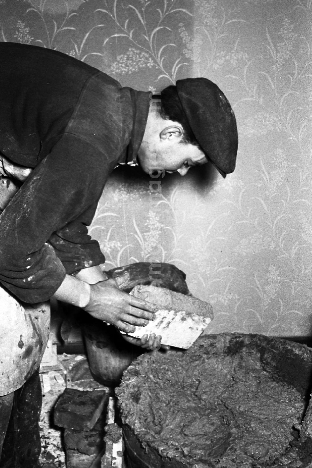 Zschopau: A stove farmer stove fitter puts a tiled stove in a flat in Zschopau in the federal state Saxony in the area of the former GDR, German democratic republic