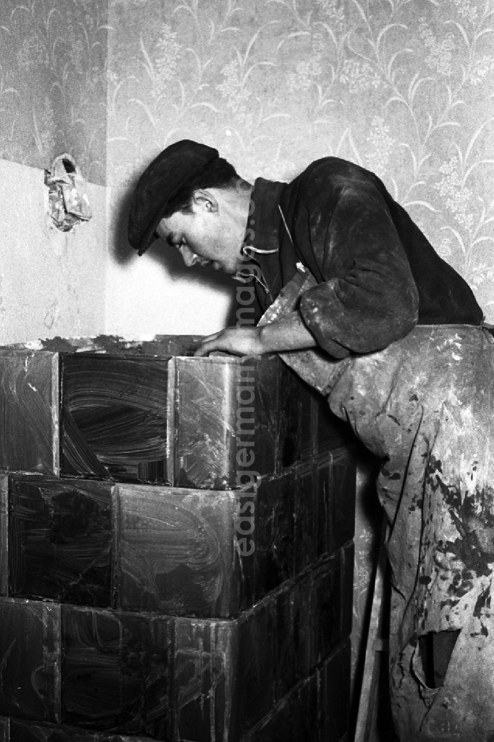 GDR image archive: Zschopau - A stove farmer stove fitter puts a tiled stove in a flat in Zschopau in the federal state Saxony in the area of the former GDR, German democratic republic