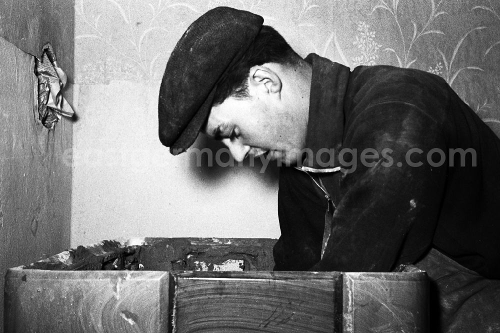 GDR photo archive: Zschopau - A stove farmer stove fitter puts a tiled stove in a flat in Zschopau in the federal state Saxony in the area of the former GDR, German democratic republic