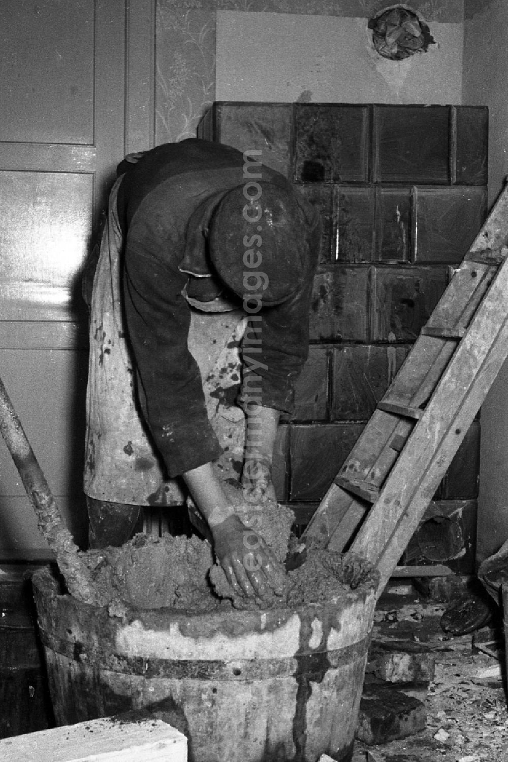 GDR picture archive: Zschopau - A stove farmer stove fitter puts a tiled stove in a flat in Zschopau in the federal state Saxony in the area of the former GDR, German democratic republic