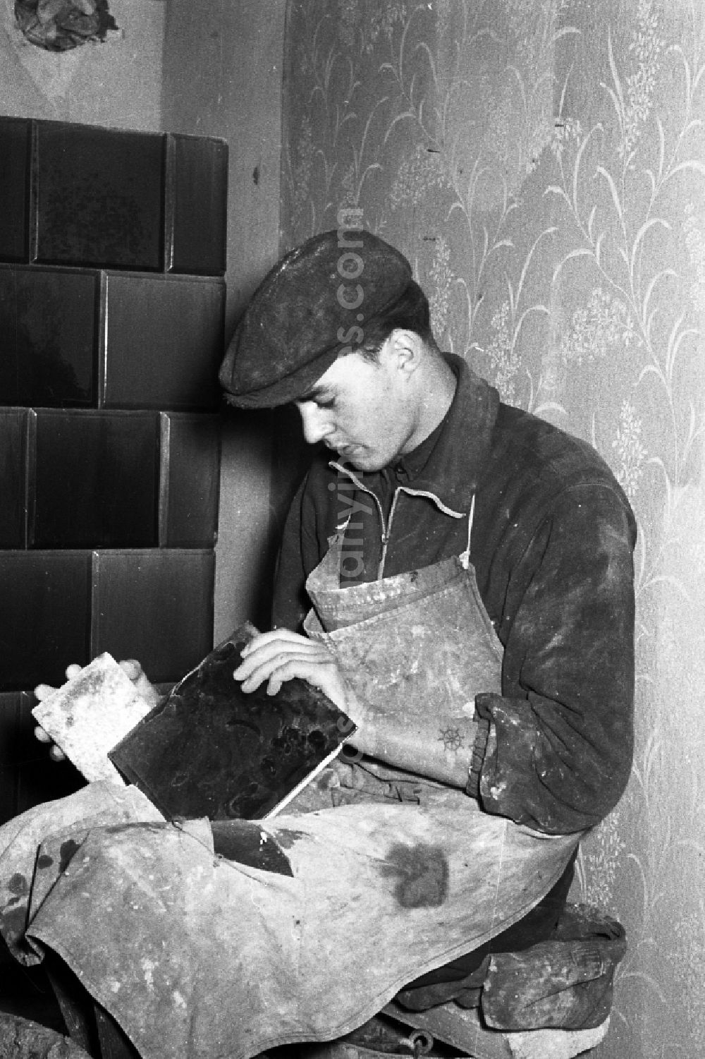 Zschopau: A stove farmer stove fitter puts a tiled stove in a flat in Zschopau in the federal state Saxony in the area of the former GDR, German democratic republic