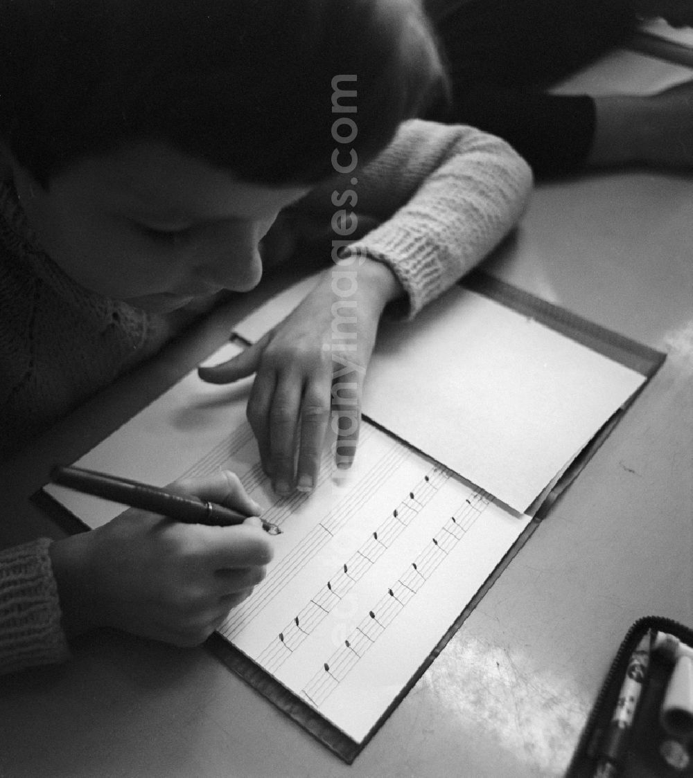 GDR picture archive: Berlin - A student writes with pen notes in his book of music in Berlin