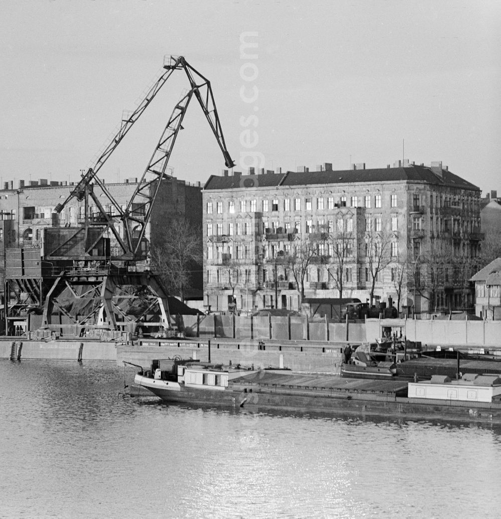 GDR picture archive: Berlin - A heavy-duty crane at the riverside in the east port - Port Industry in Berlin. In the background houses at Stralauer Allee. In the foreground a transport barge