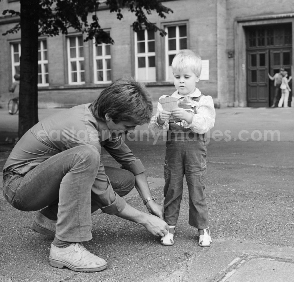 GDR picture archive: Berlin - A father binds his child's shoes, in Berlin, the former capital of the GDR, the German Democratic Republic