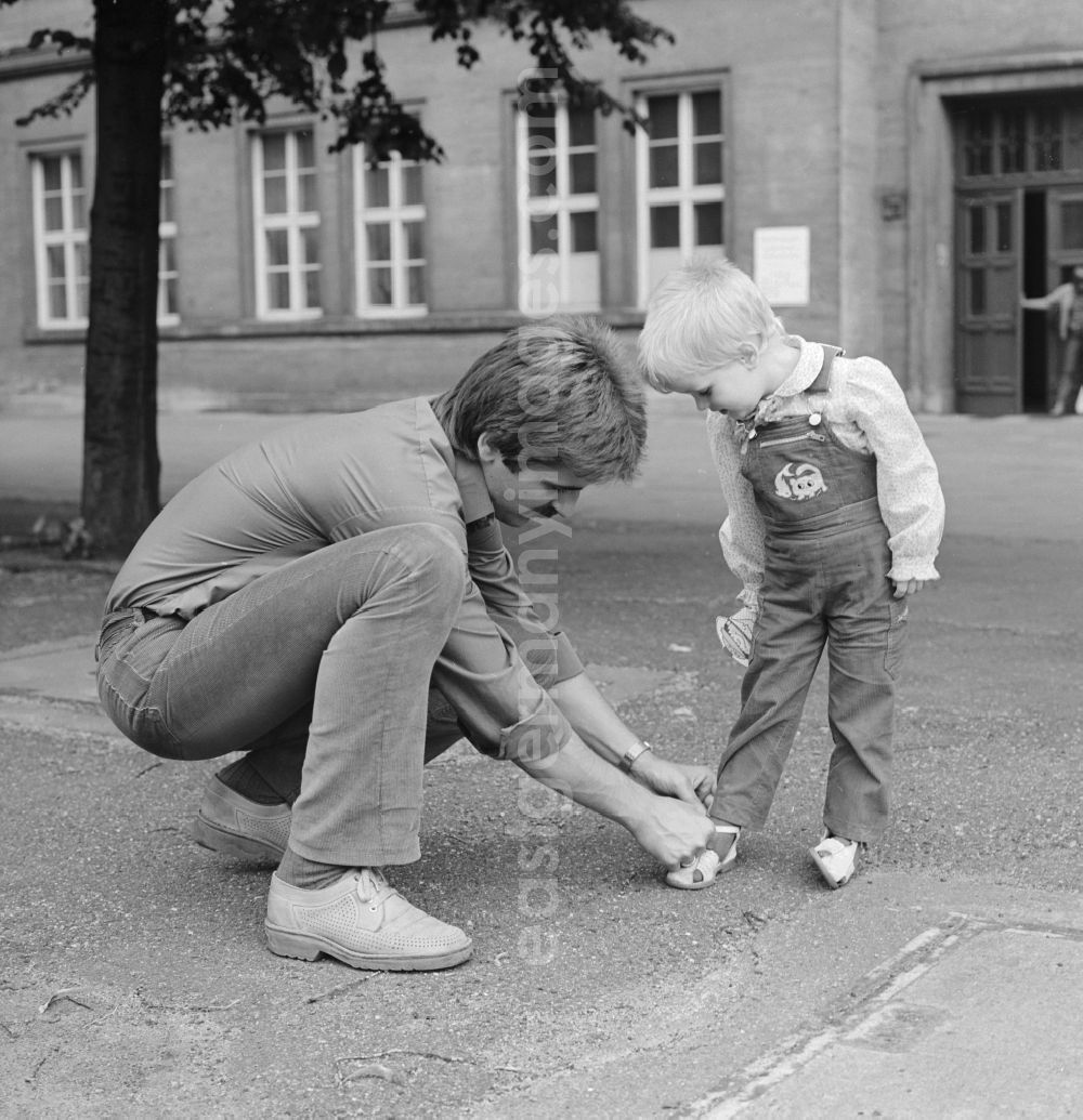 Berlin: A father binds his child's shoes, in Berlin, the former capital of the GDR, the German Democratic Republic