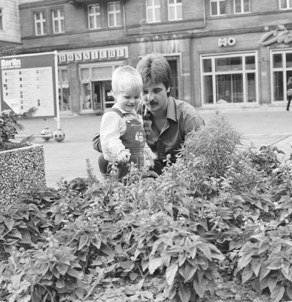 Berlin: A father is holding his child in front of a flower bed in the Karl-Marx-Allee in Berlin, the former capital of the GDR, the German Democratic Republic