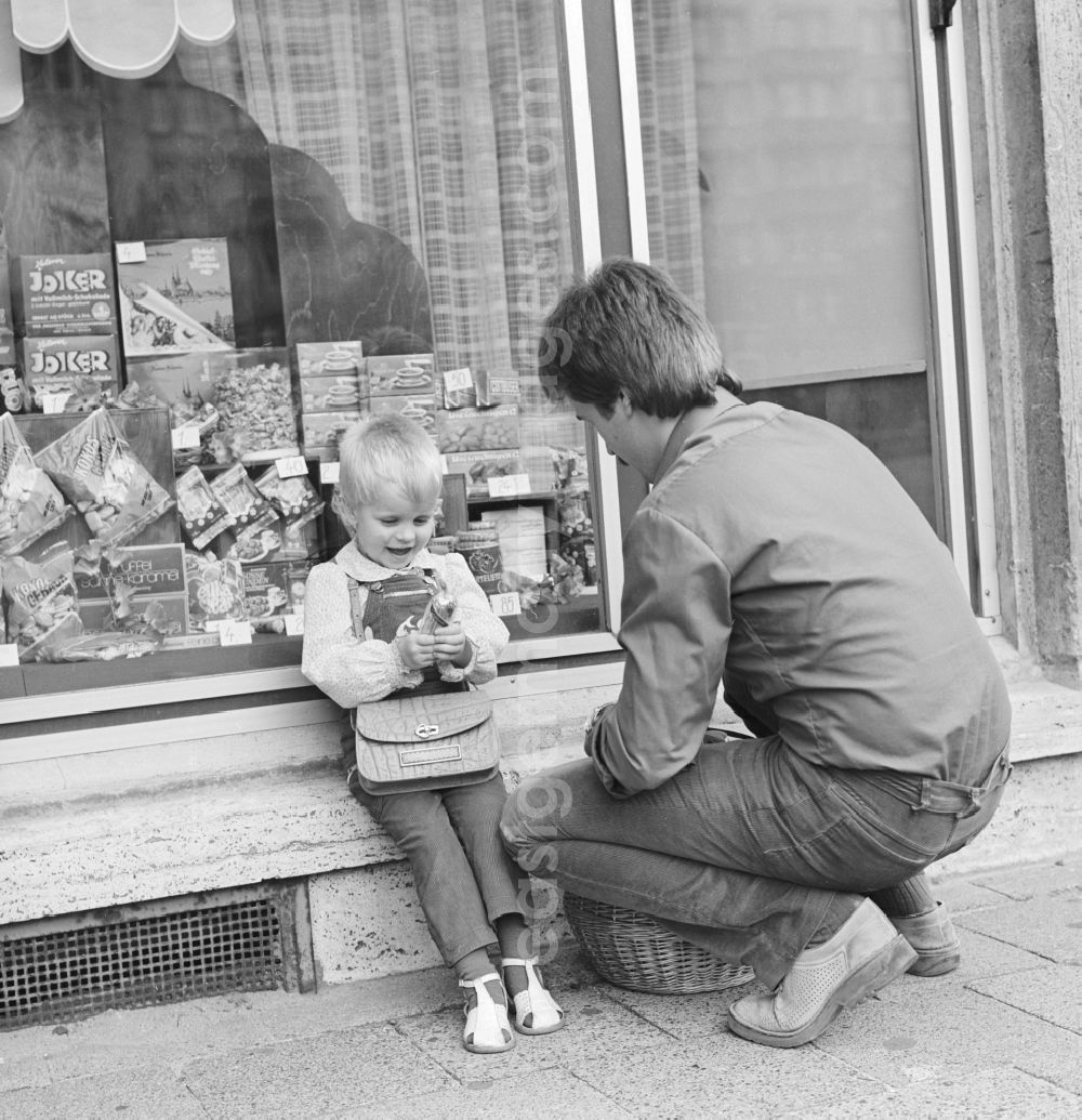 GDR photo archive: Berlin - A father is KONSUM -lding his child in front of a KONSUM - grocers in the district Friedrichshain in Berlin, the former capital of the GDR, the German Democratic Republic