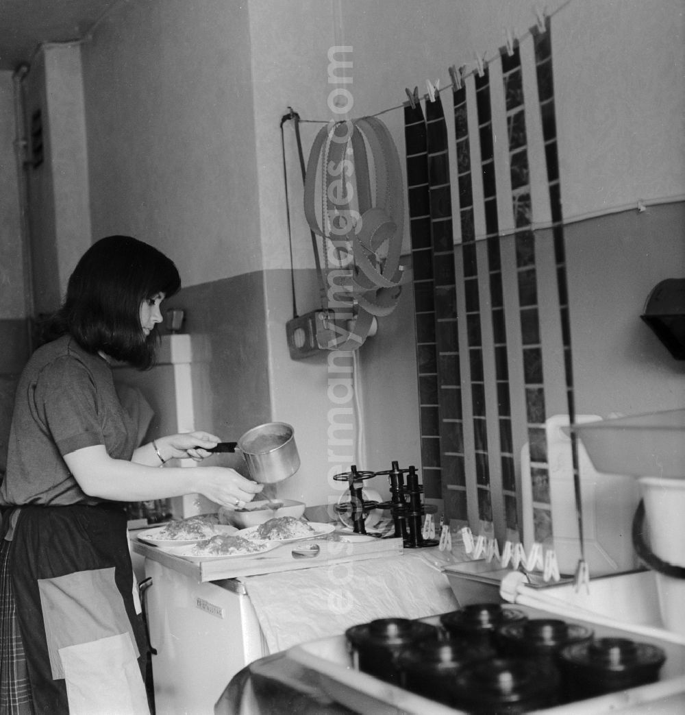 GDR photo archive: Berlin - A woman prepares food while suspended in the kitchen Films drying in Berlin, the former capital of the GDR, the German Democratic Republic