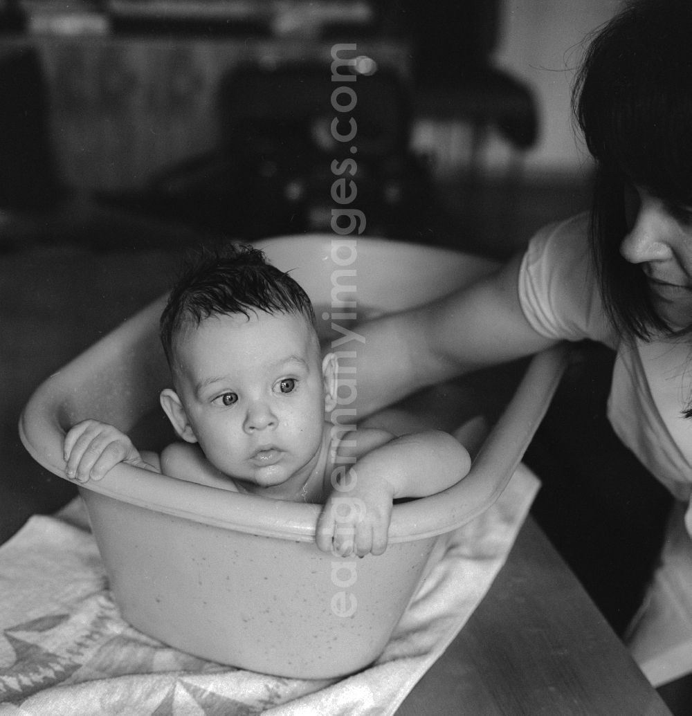 GDR photo archive: Berlin - A mother bathes her baby in a plastic tub in Berlin, the former capital of the GDR, the German Democratic Republic